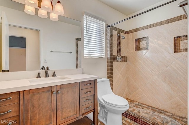 bathroom with tiled shower, toilet, an inviting chandelier, and vanity