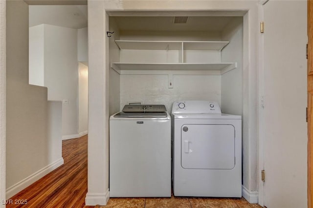 laundry area featuring baseboards, independent washer and dryer, wood finished floors, and laundry area