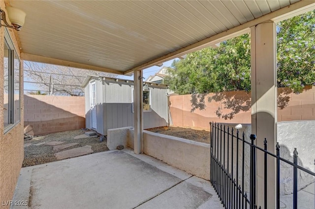 view of patio featuring a storage unit, an outbuilding, and a fenced backyard