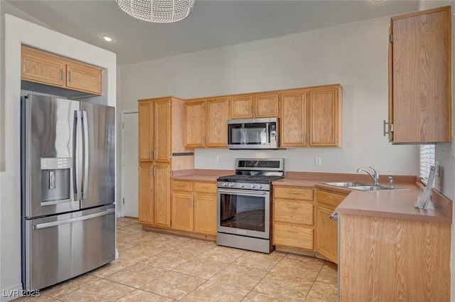 kitchen featuring light brown cabinets, stainless steel appliances, and a sink