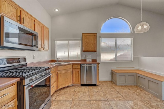 kitchen featuring high vaulted ceiling, pendant lighting, a sink, stainless steel appliances, and light tile patterned flooring