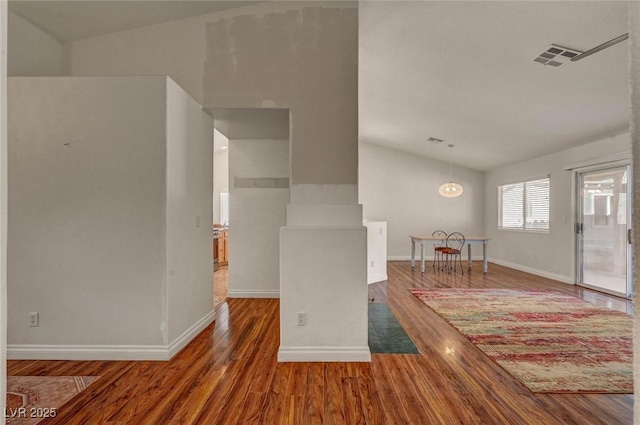 interior space with visible vents, baseboards, wood finished floors, and vaulted ceiling