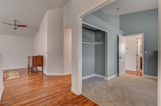 carpeted bedroom featuring vaulted ceiling, wood finished floors, baseboards, and a closet