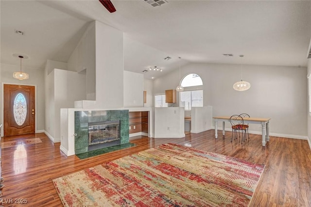 living area featuring a tiled fireplace, wood finished floors, and baseboards