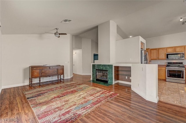 kitchen featuring a ceiling fan, visible vents, stainless steel appliances, a tiled fireplace, and open floor plan