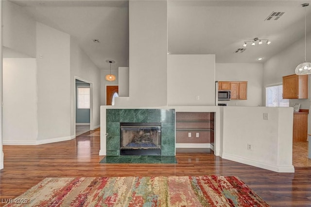 unfurnished living room with visible vents, a healthy amount of sunlight, a fireplace, and wood finished floors