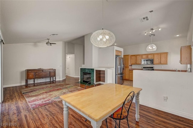 kitchen with stainless steel appliances, visible vents, wood finished floors, and a tiled fireplace