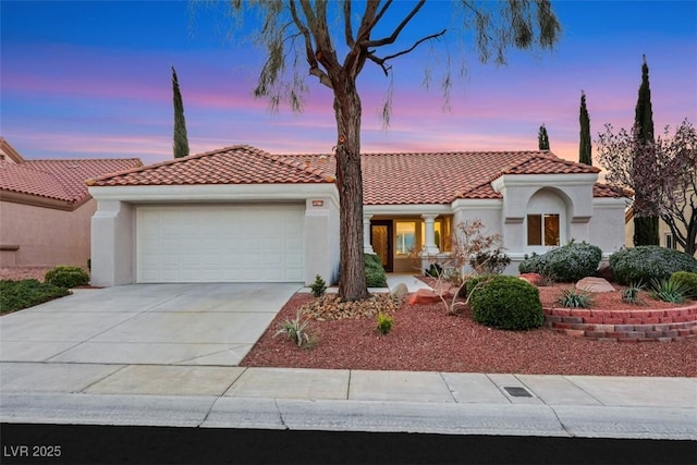 mediterranean / spanish house featuring an attached garage, driveway, and stucco siding