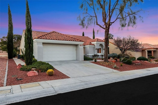 mediterranean / spanish house featuring a tiled roof, a garage, driveway, and stucco siding