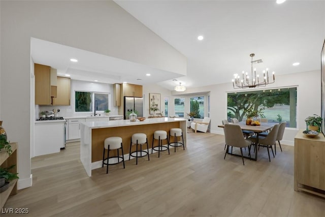 kitchen featuring a kitchen island, a breakfast bar area, light countertops, lofted ceiling, and stainless steel refrigerator with ice dispenser