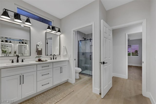 full bath featuring a sink, baseboards, wood finished floors, and a shower stall