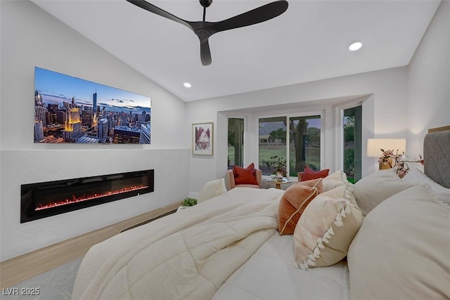 bedroom with wood finished floors, a glass covered fireplace, recessed lighting, ceiling fan, and vaulted ceiling