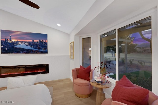 interior space featuring wood finished floors, lofted ceiling, recessed lighting, ceiling fan, and a glass covered fireplace