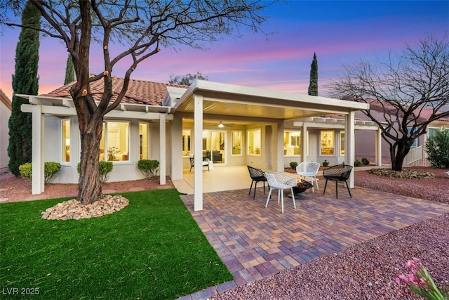 back of property featuring stucco siding, a lawn, a tile roof, and a patio area