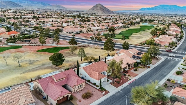 aerial view at dusk featuring golf course view, a mountain view, and a residential view