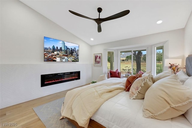 bedroom featuring vaulted ceiling, recessed lighting, wood finished floors, a glass covered fireplace, and a ceiling fan