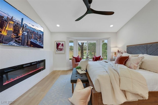 bedroom with a glass covered fireplace, lofted ceiling, recessed lighting, and wood finished floors