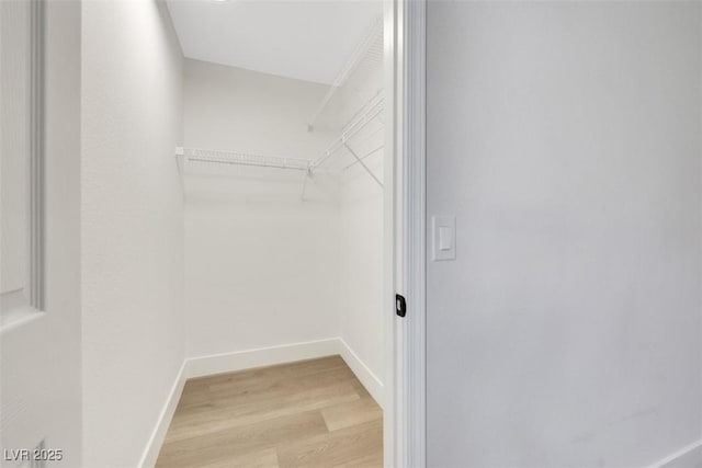 walk in closet with wood finished floors