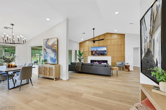 dining area featuring a glass covered fireplace, high vaulted ceiling, light wood-type flooring, and visible vents