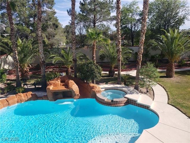 view of pool with fence and a pool with connected hot tub