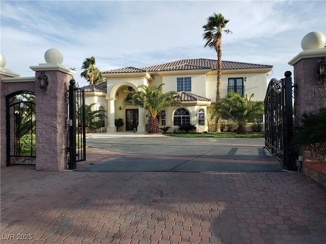 view of front of house featuring stucco siding, a tile roof, and a gate