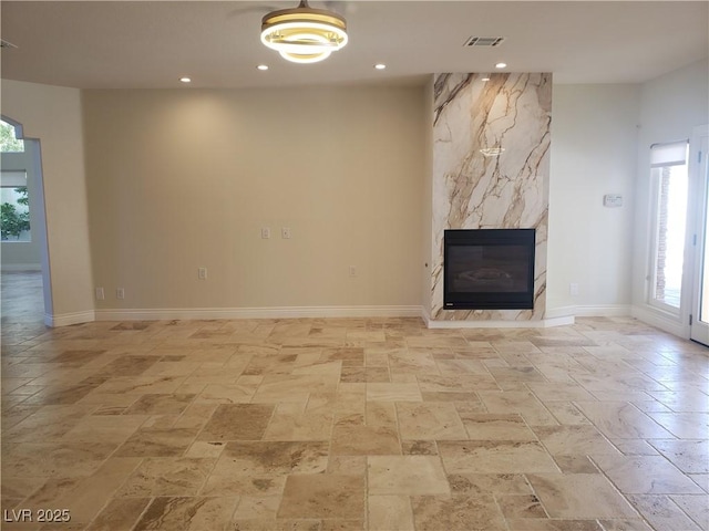 unfurnished living room featuring visible vents, baseboards, recessed lighting, stone tile flooring, and a large fireplace