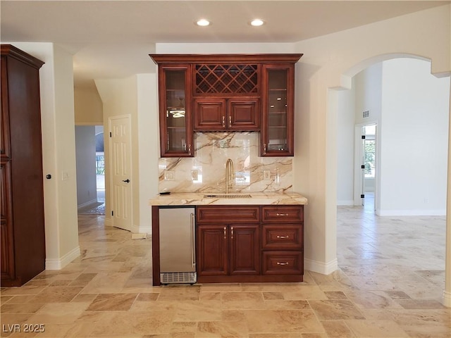 bar with indoor wet bar, arched walkways, a wealth of natural light, and a sink