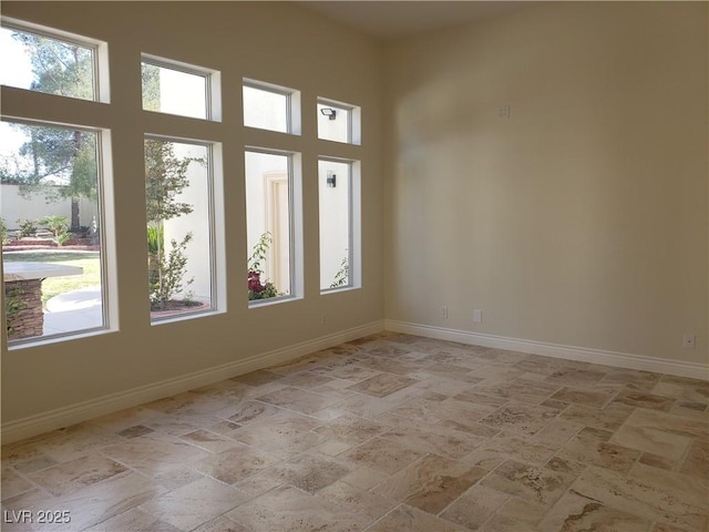 empty room featuring baseboards and a towering ceiling