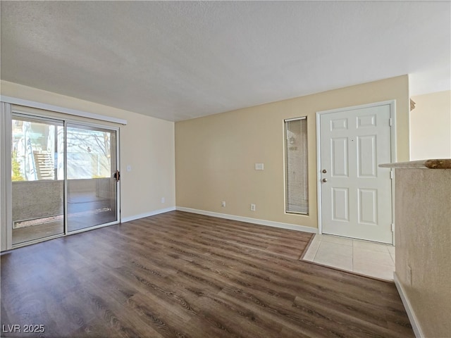 interior space featuring a textured ceiling, baseboards, and wood finished floors