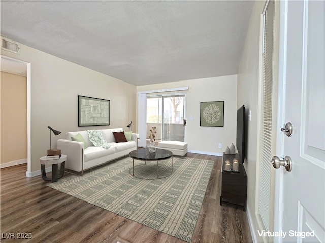 living room featuring visible vents, baseboards, and wood finished floors