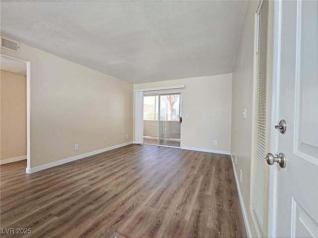 unfurnished room featuring dark wood finished floors, baseboards, and visible vents