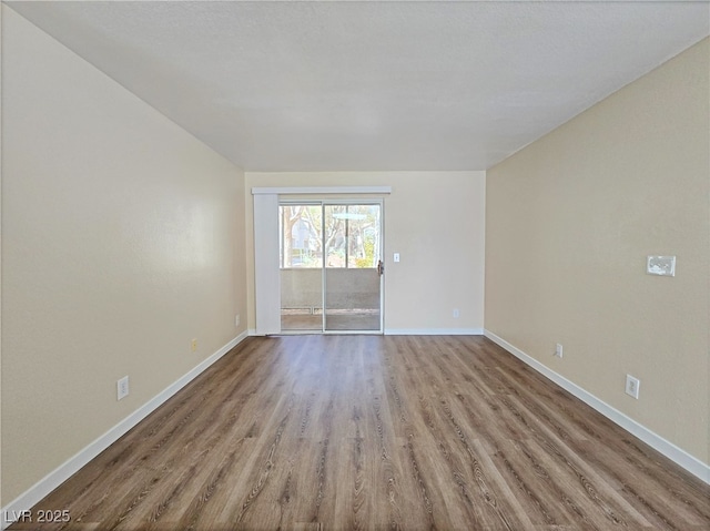 empty room featuring wood finished floors and baseboards