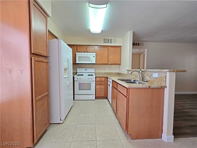 kitchen with a sink, visible vents, white appliances, and a peninsula