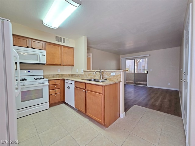 kitchen with white appliances, visible vents, a peninsula, light tile patterned flooring, and a sink