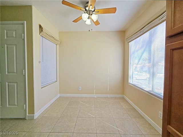 empty room featuring light tile patterned floors, a ceiling fan, and baseboards