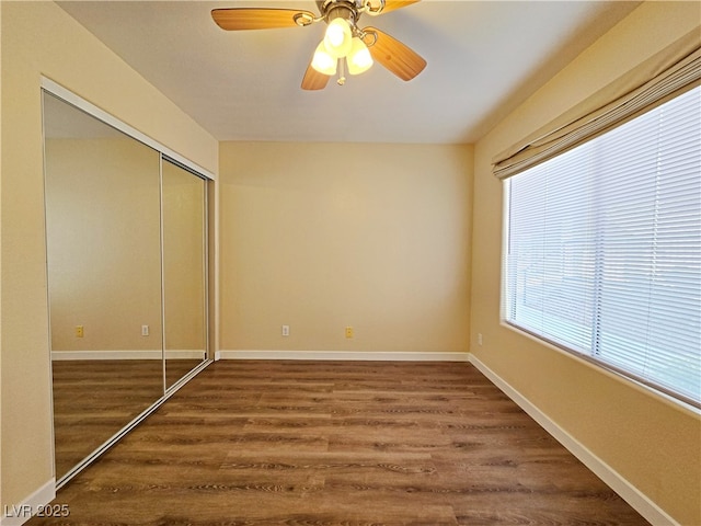 unfurnished bedroom with baseboards, a closet, dark wood-style flooring, and ceiling fan