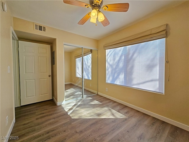 unfurnished bedroom featuring a closet, visible vents, baseboards, and wood finished floors