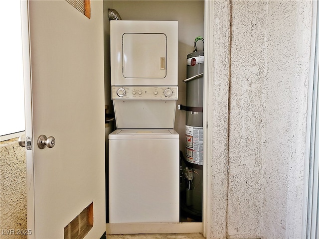 laundry area with laundry area, gas water heater, and stacked washer and dryer