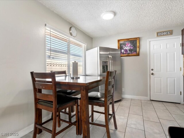 dining space featuring baseboards, a textured ceiling, and light tile patterned flooring