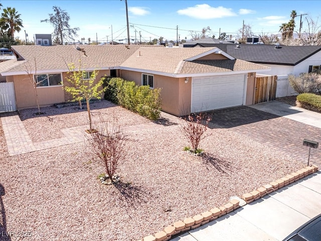 ranch-style house featuring stucco siding, roof with shingles, driveway, and fence