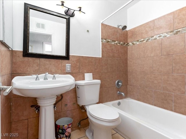 full bath with tile walls, visible vents, toilet, and bathing tub / shower combination