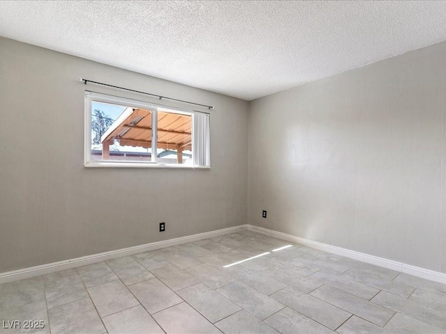 spare room featuring baseboards and a textured ceiling