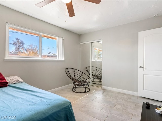 bedroom with baseboards, multiple windows, a closet, and a ceiling fan