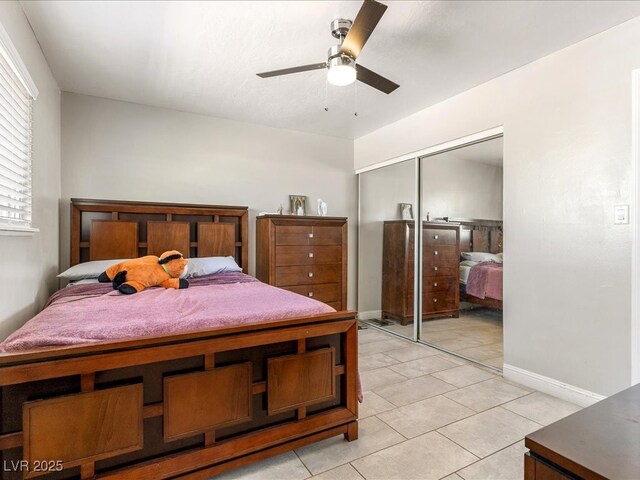 bedroom featuring a closet, light tile patterned floors, ceiling fan, and baseboards