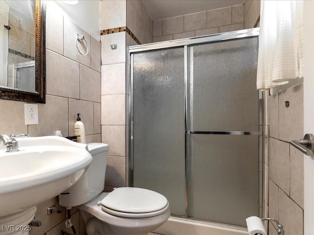 full bath with tile walls, toilet, a shower stall, and a sink