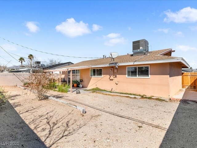 rear view of property with cooling unit, a fenced backyard, roof with shingles, and stucco siding