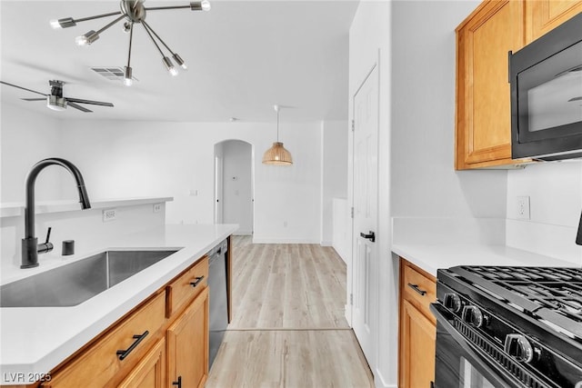 kitchen featuring visible vents, black appliances, light wood-style flooring, a sink, and arched walkways