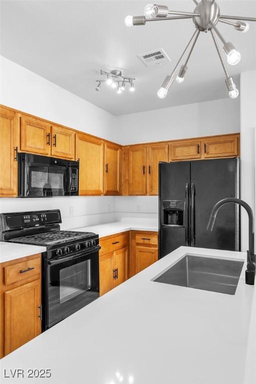 kitchen featuring black appliances, light countertops, visible vents, and a sink