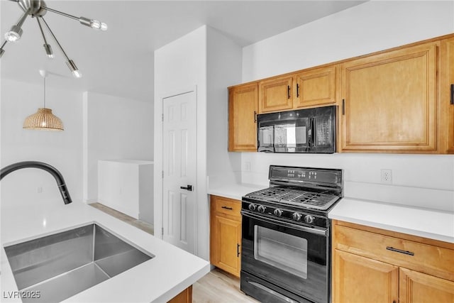 kitchen featuring pendant lighting, black appliances, light countertops, and a sink