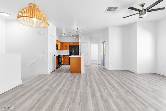 kitchen with visible vents, open floor plan, light countertops, brown cabinetry, and black appliances